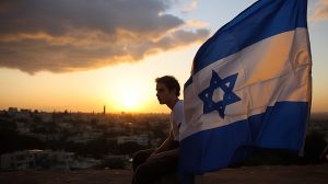 молодой репатриант на фоне флага Израиля