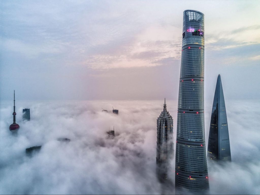 Shanghai Tower выступает сквозь море тумана в зарождающемся свете утра